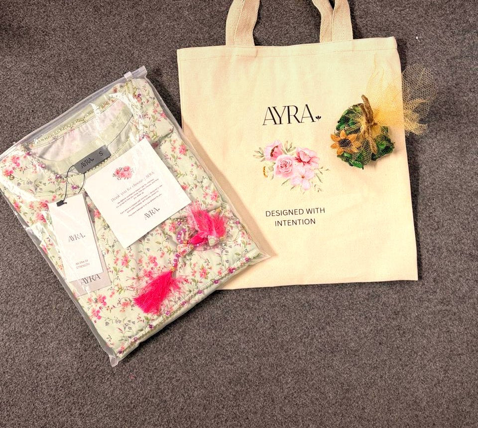 An Ayra order: garment folded into a keepsake tote with a hand-tied posy and a thank-you note.